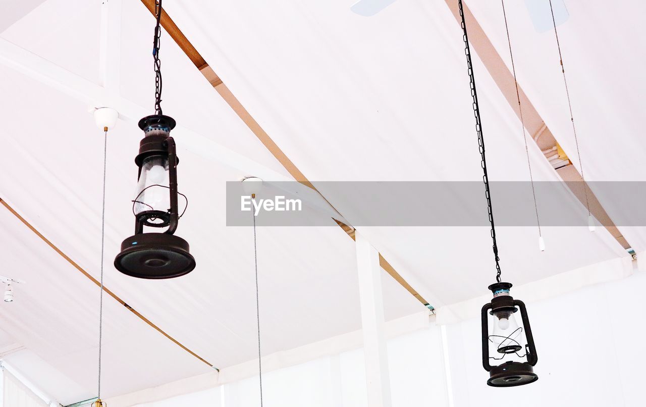LOW ANGLE VIEW OF ELECTRIC LAMP HANGING ON CABLE