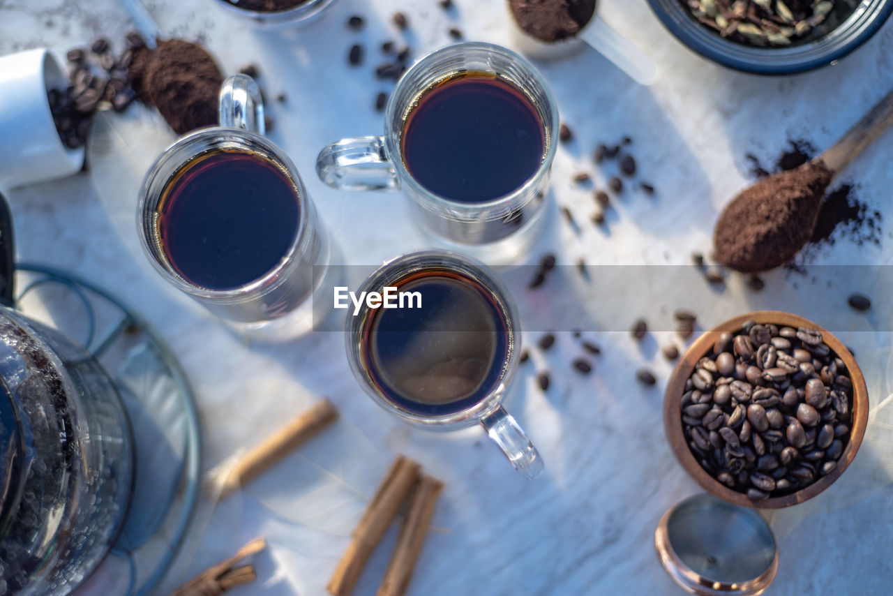 Still life with glass mugs of black hot coffee, coffee beans, making coffee at home