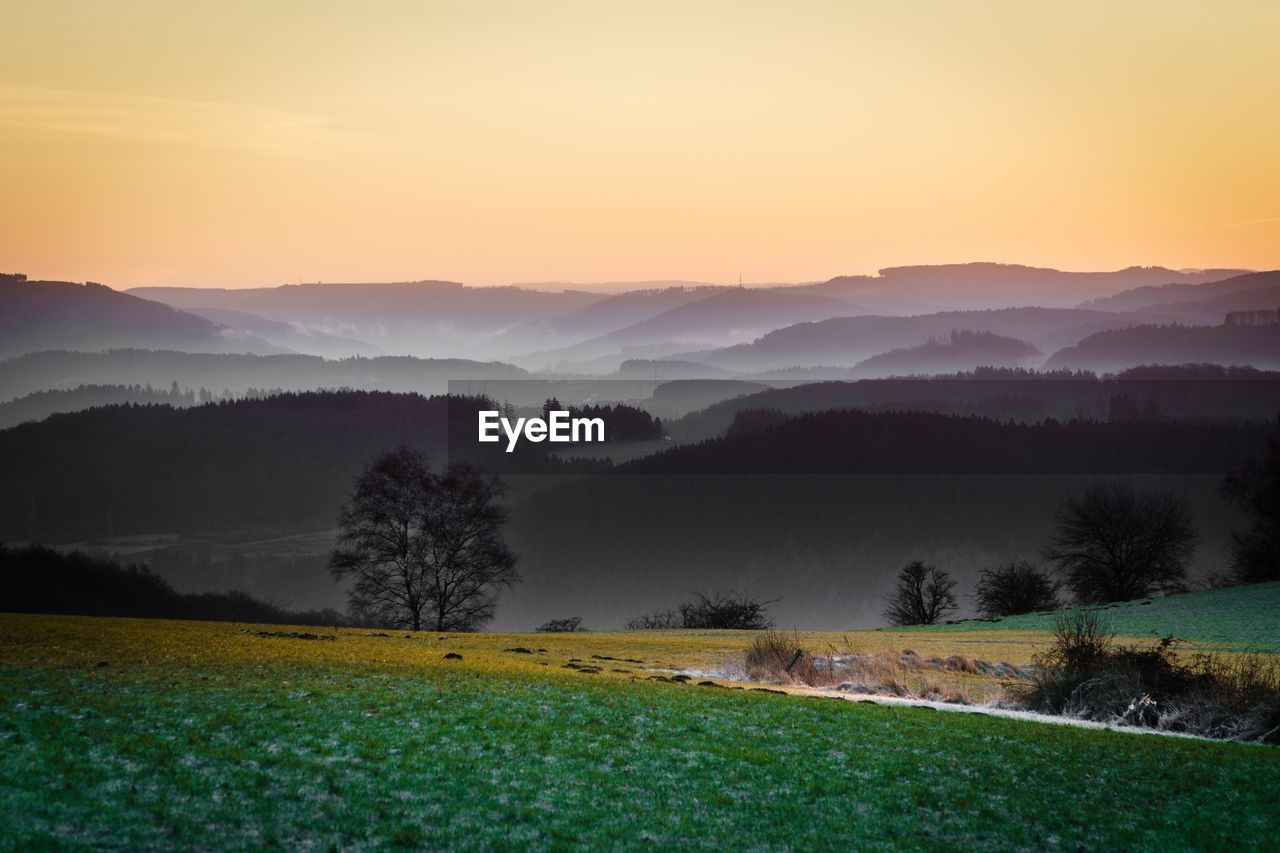 Scenic view of field against mountains during sunset