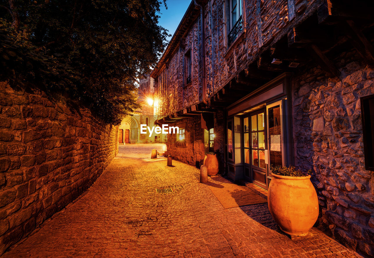 Illuminated street amidst buildings at night