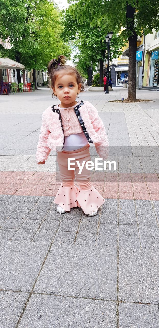 Portrait of cute girl standing on footpath