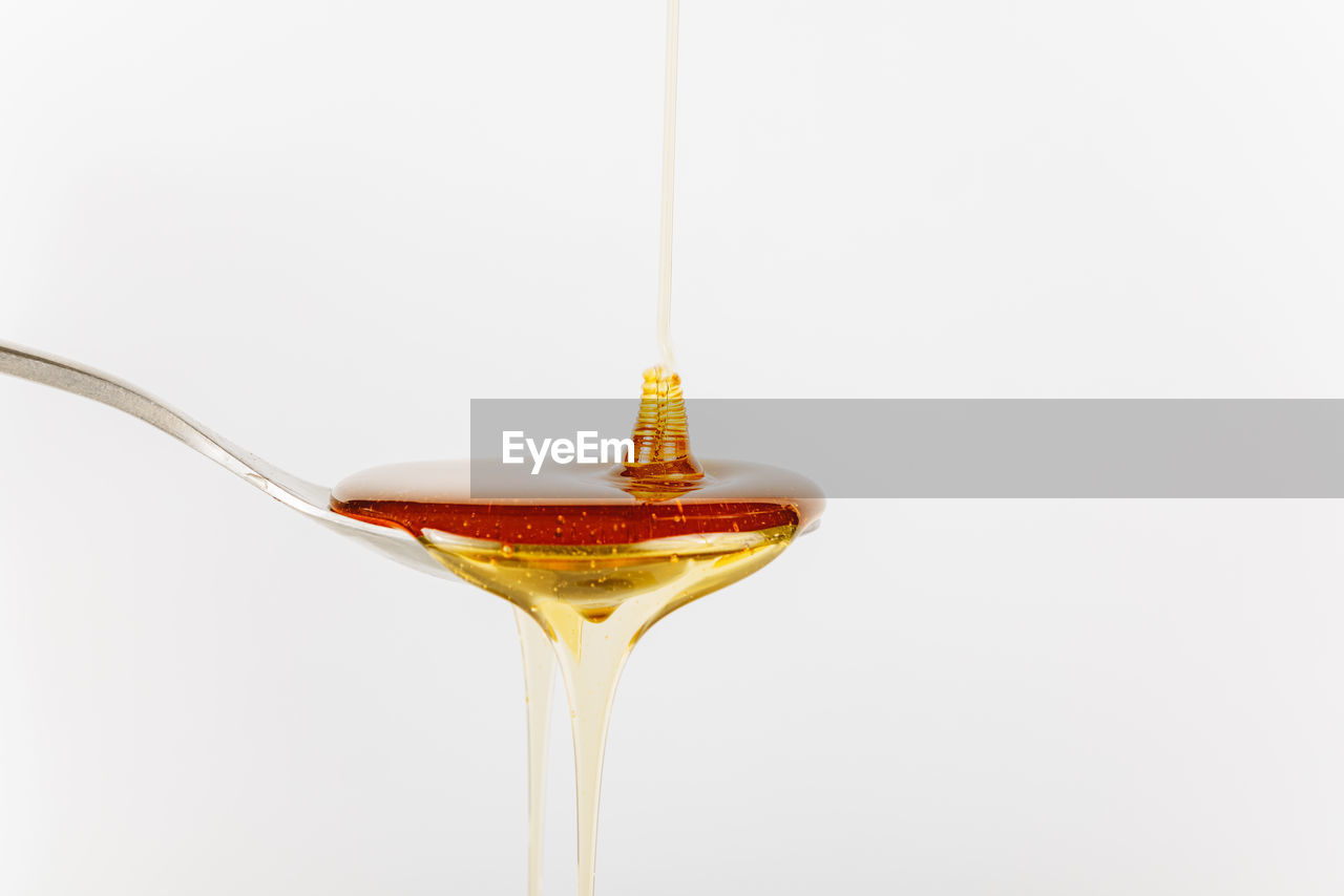 Close up of honey being poured into a silver spoon, honey is a natural sweetener as a substitute