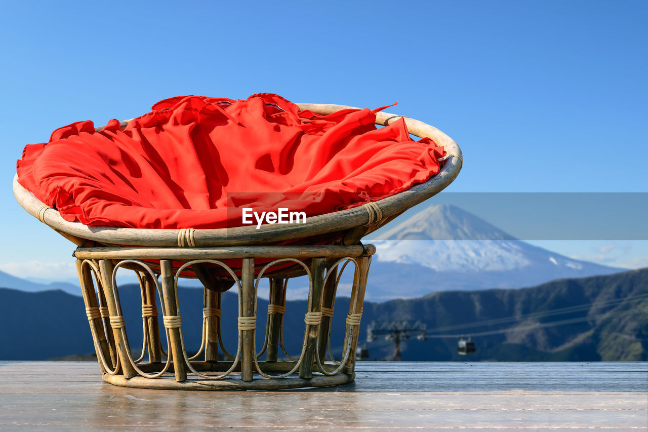 Chairs made of rattan and upholstery fabrics in red on wooden terrace with mount fuji background.