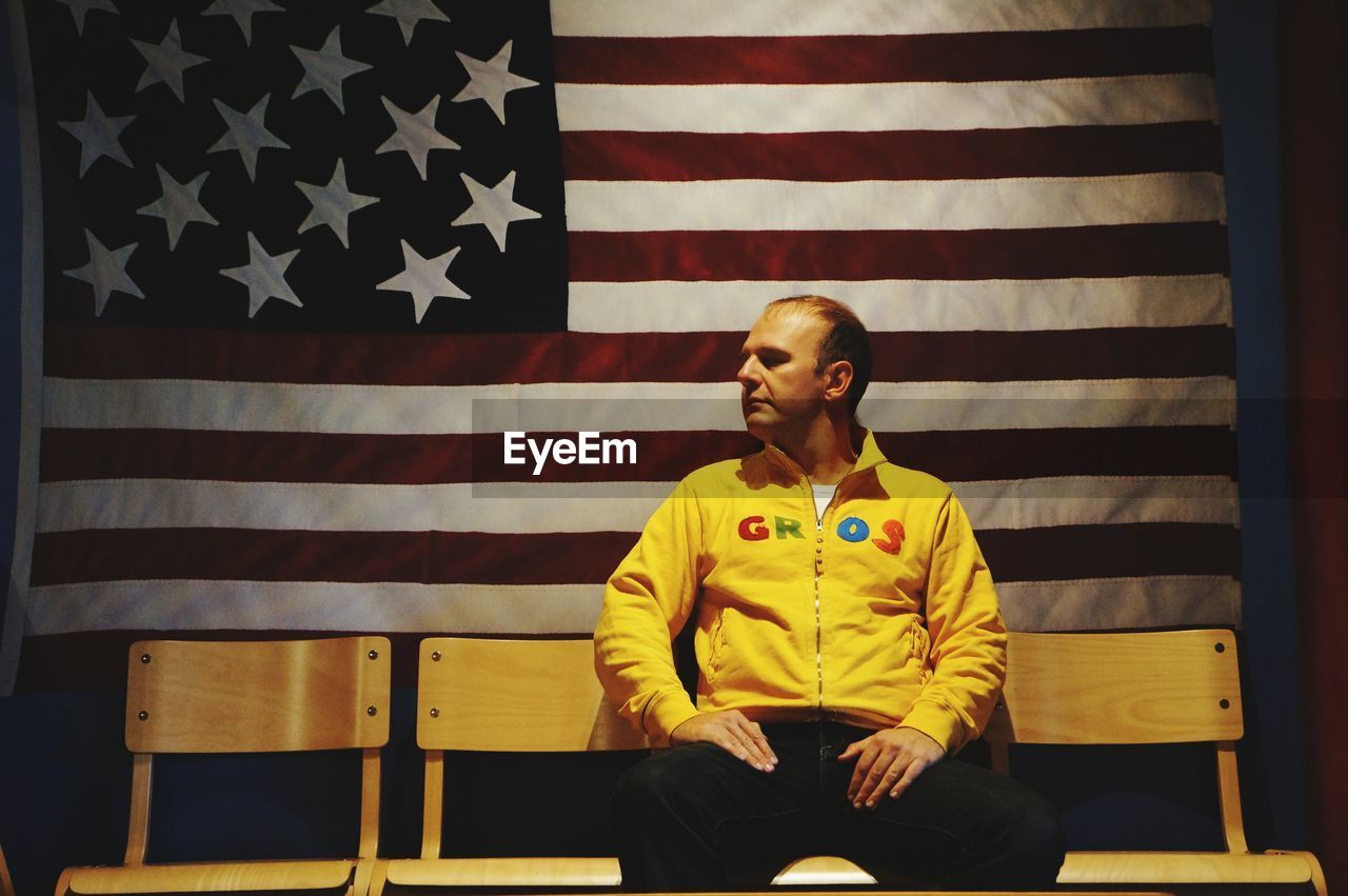 Man sitting on chair against american flag