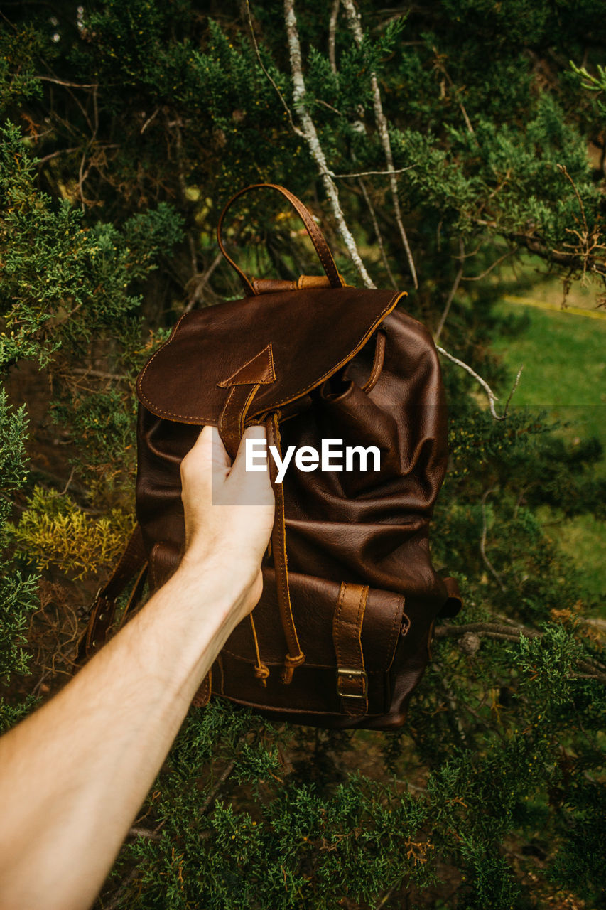 Man holding backpack against trees