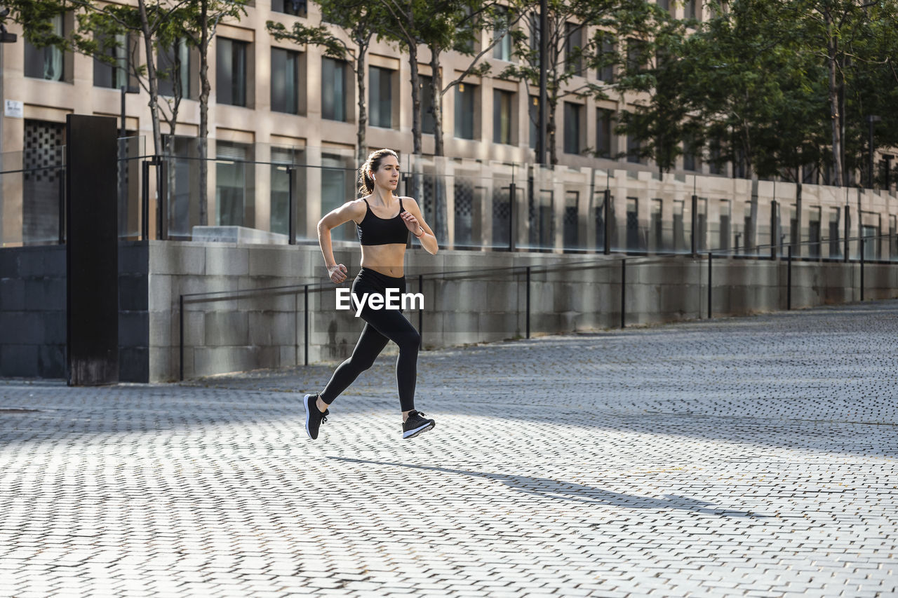 Woman in sportswear jogging on footpath