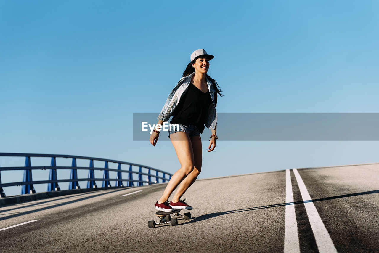 Woman skateboarding against blue sky