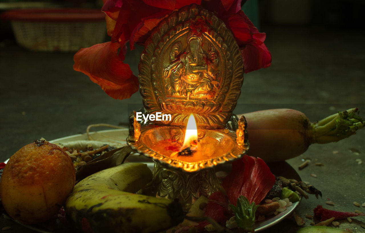 Ganesha idol and burning diya in plate