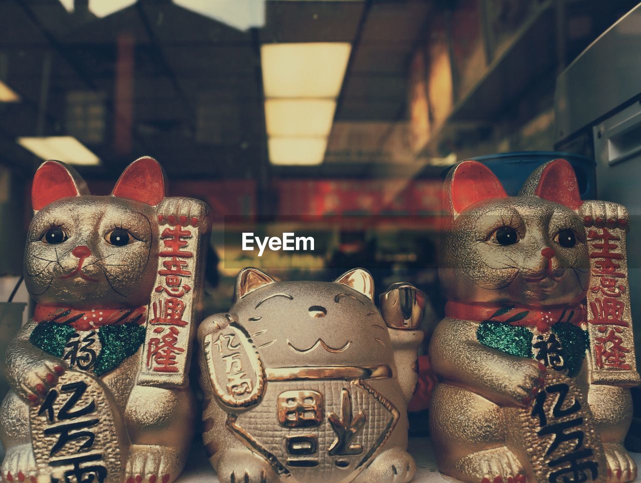 Maneki nekos seen through glass at store for sale