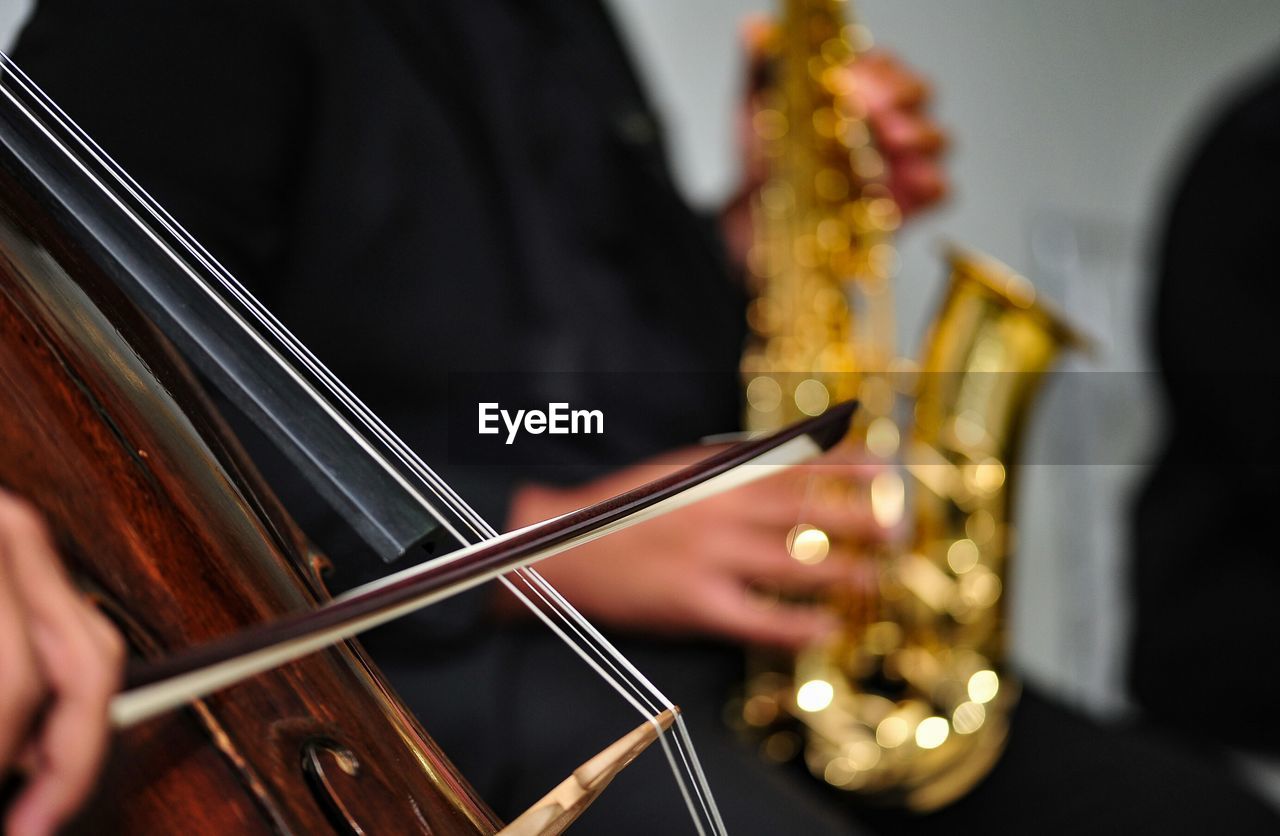 Cropped image of people playing violin and saxophone