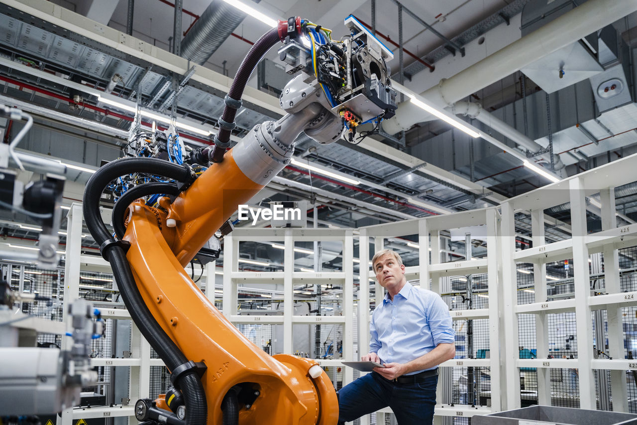 Businessman examining industrial robot in a factory