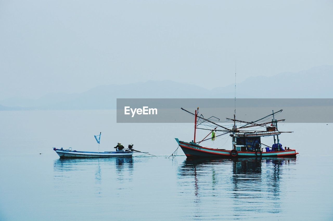 Boats moored in sea against clear sky