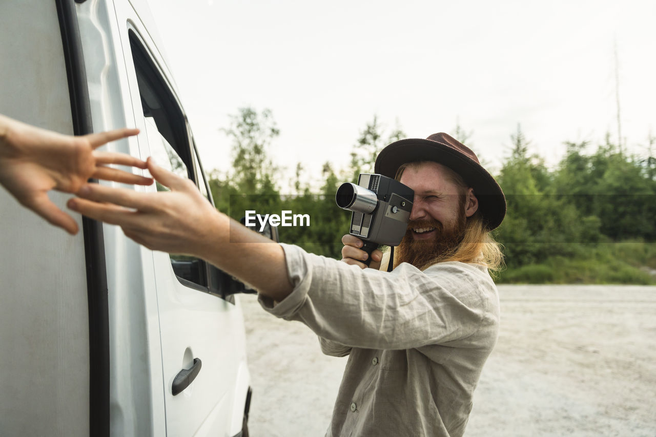 Boyfriend photographing girlfriend while standing by motor home