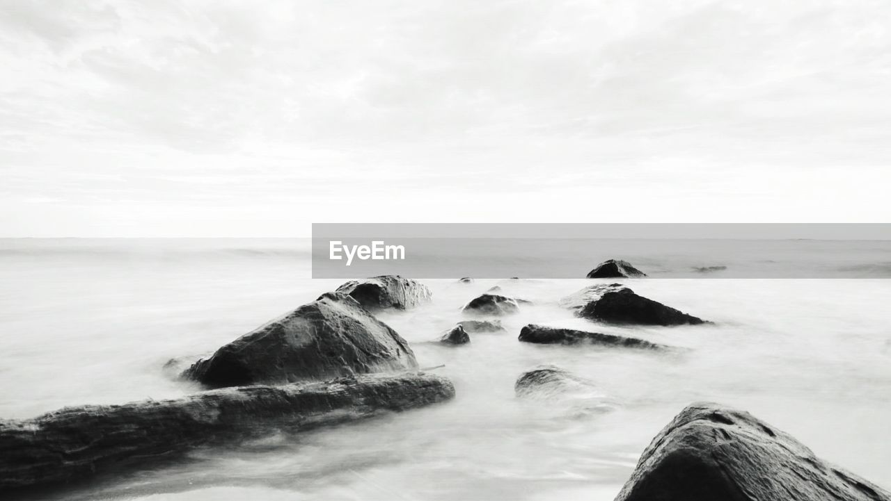 ROCKS IN SEA AGAINST SKY