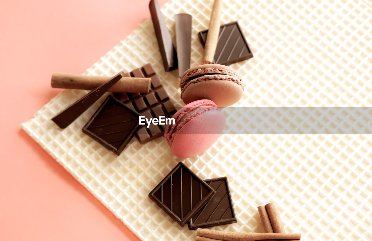 Macarons, chocolates, cinnamon sticks on waffle background. sweet food concept.