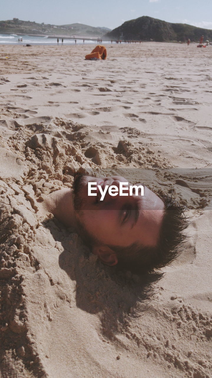 Portrait of man buried in sand at beach