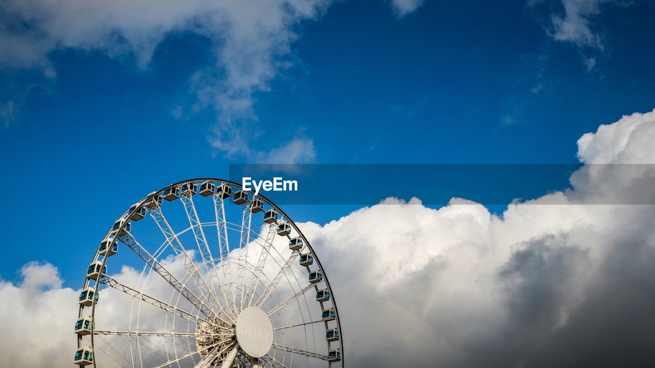 Cropped image of ferris wheel against cloudy sky