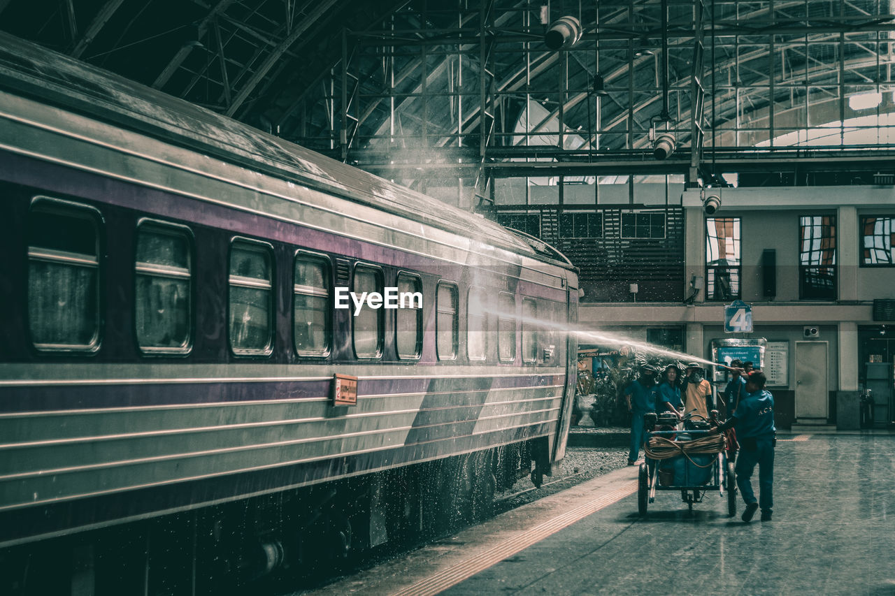 People cleaning train on railroad station platform