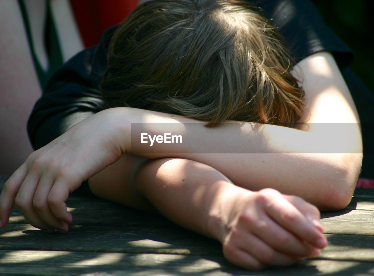 Close-up of tired boy sleeping on table