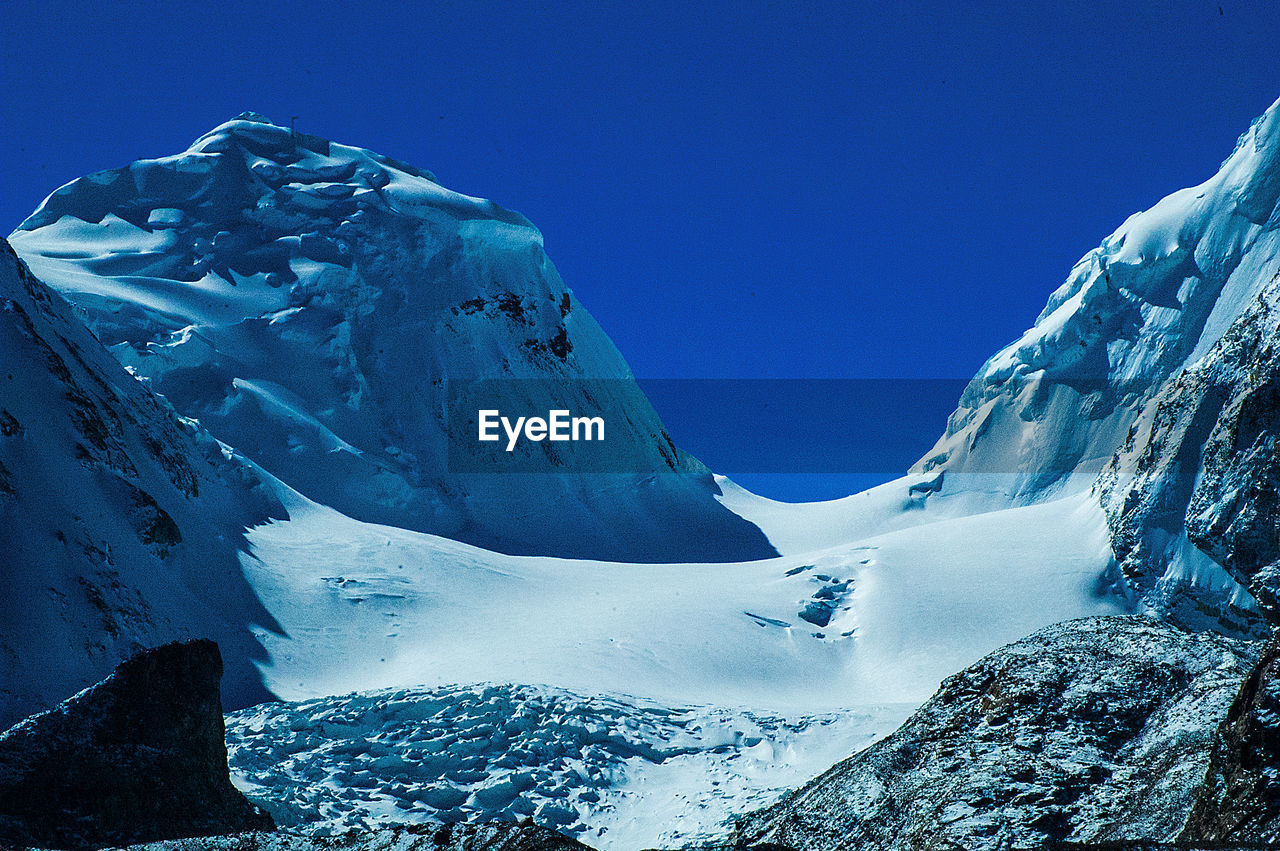 AERIAL VIEW OF SNOWCAPPED MOUNTAINS AGAINST BLUE SKY