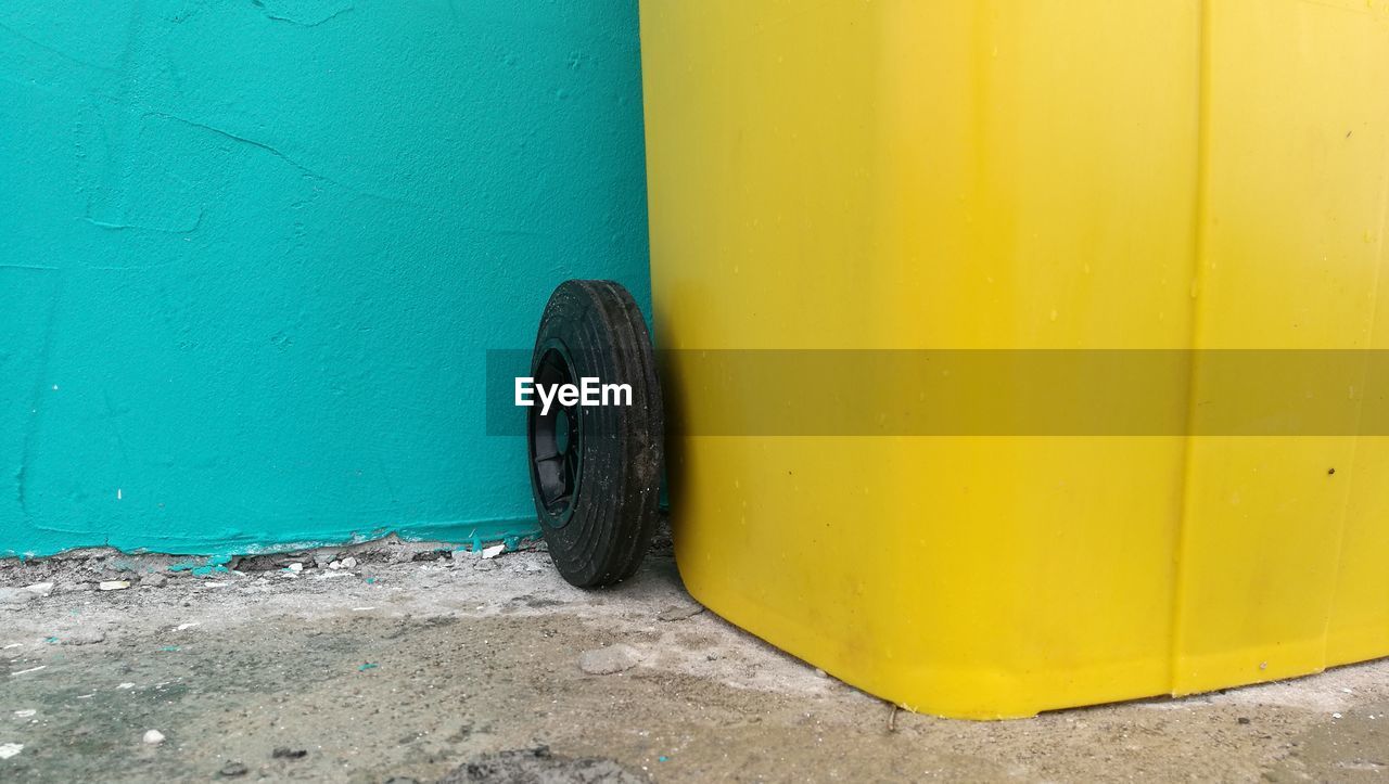 CLOSE-UP OF YELLOW TIRE ON CONCRETE WALL