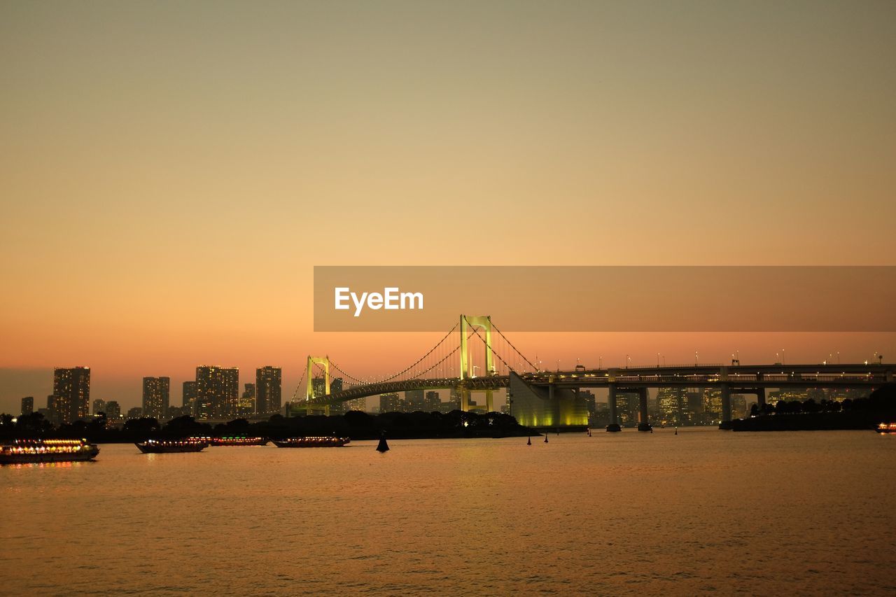 View of suspension bridge in city at sunset