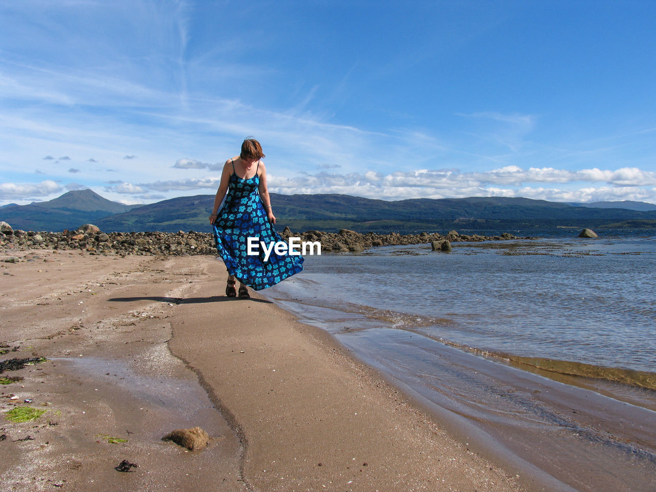 Woman wearing dress while walking on shore at beach