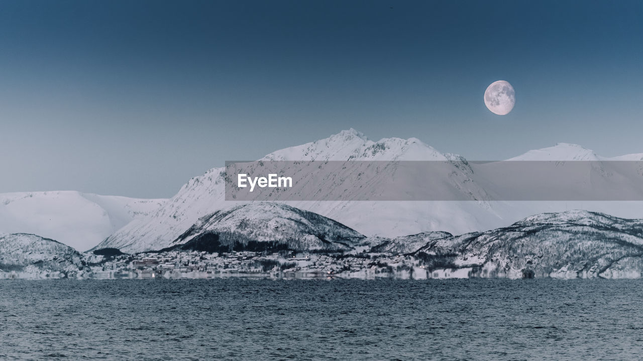 Scenic view of sea and snowcapped mountains against sky