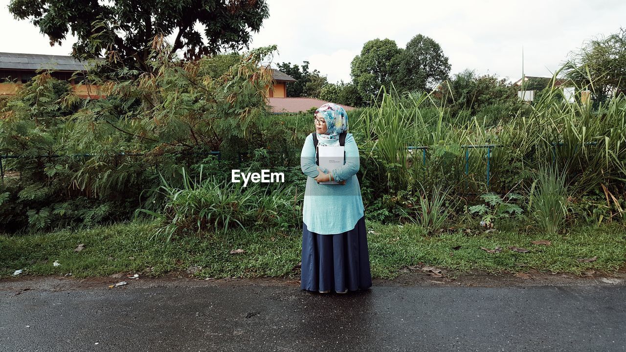 FULL LENGTH OF WOMAN STANDING ON FIELD AGAINST SKY