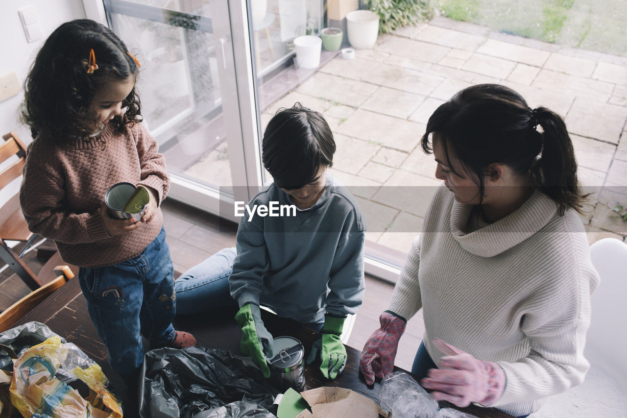 High angle view of mother with children collecting waste at home