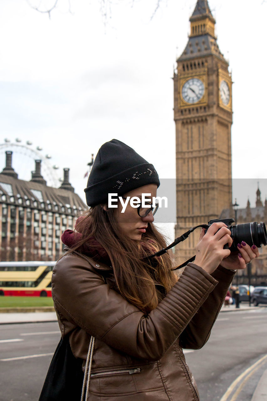 Woman photographing while standing against big ben