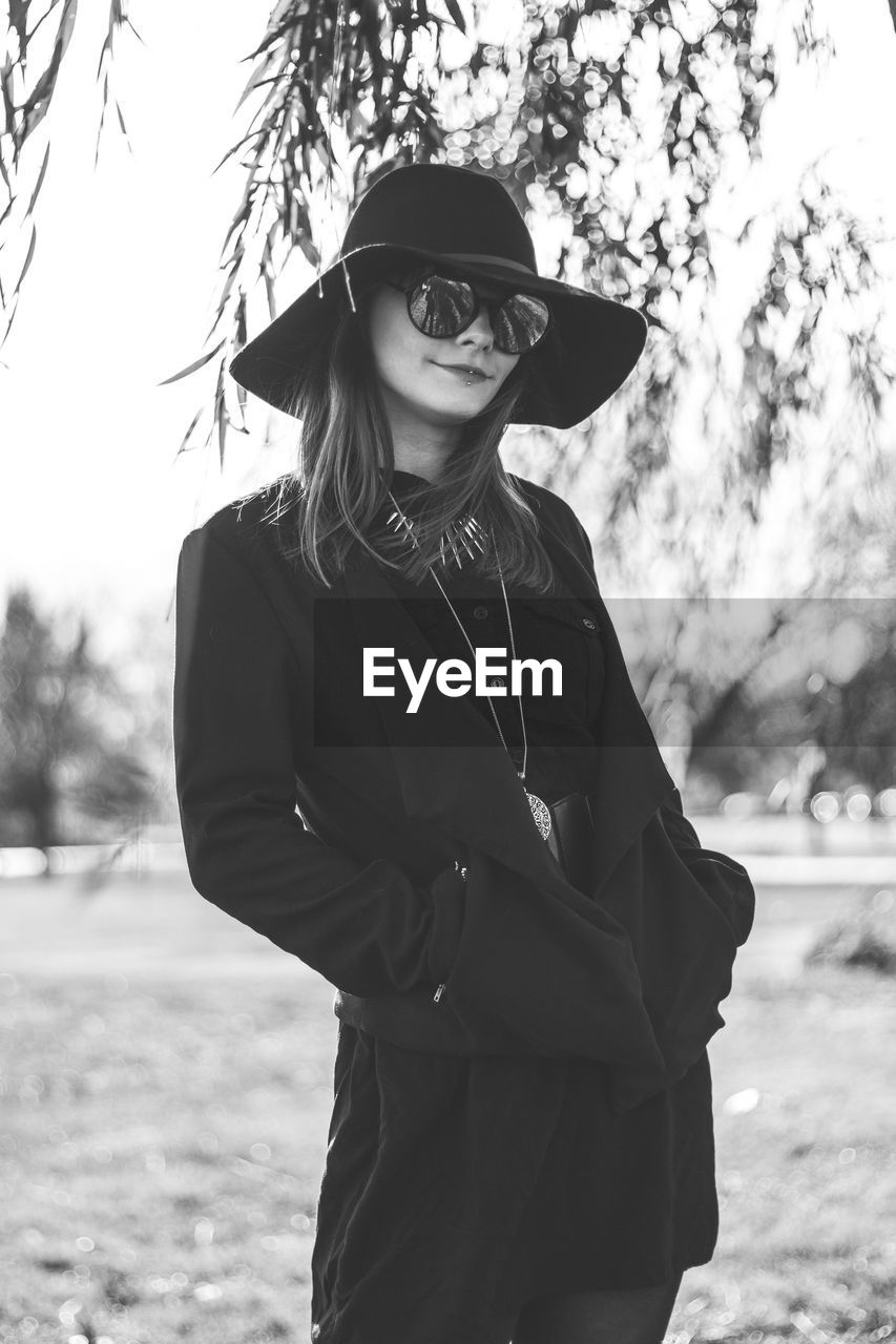 Portrait of woman standing against tree