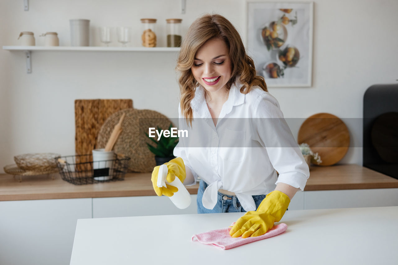 Housewife in yellow gloves wipes the kitchen table