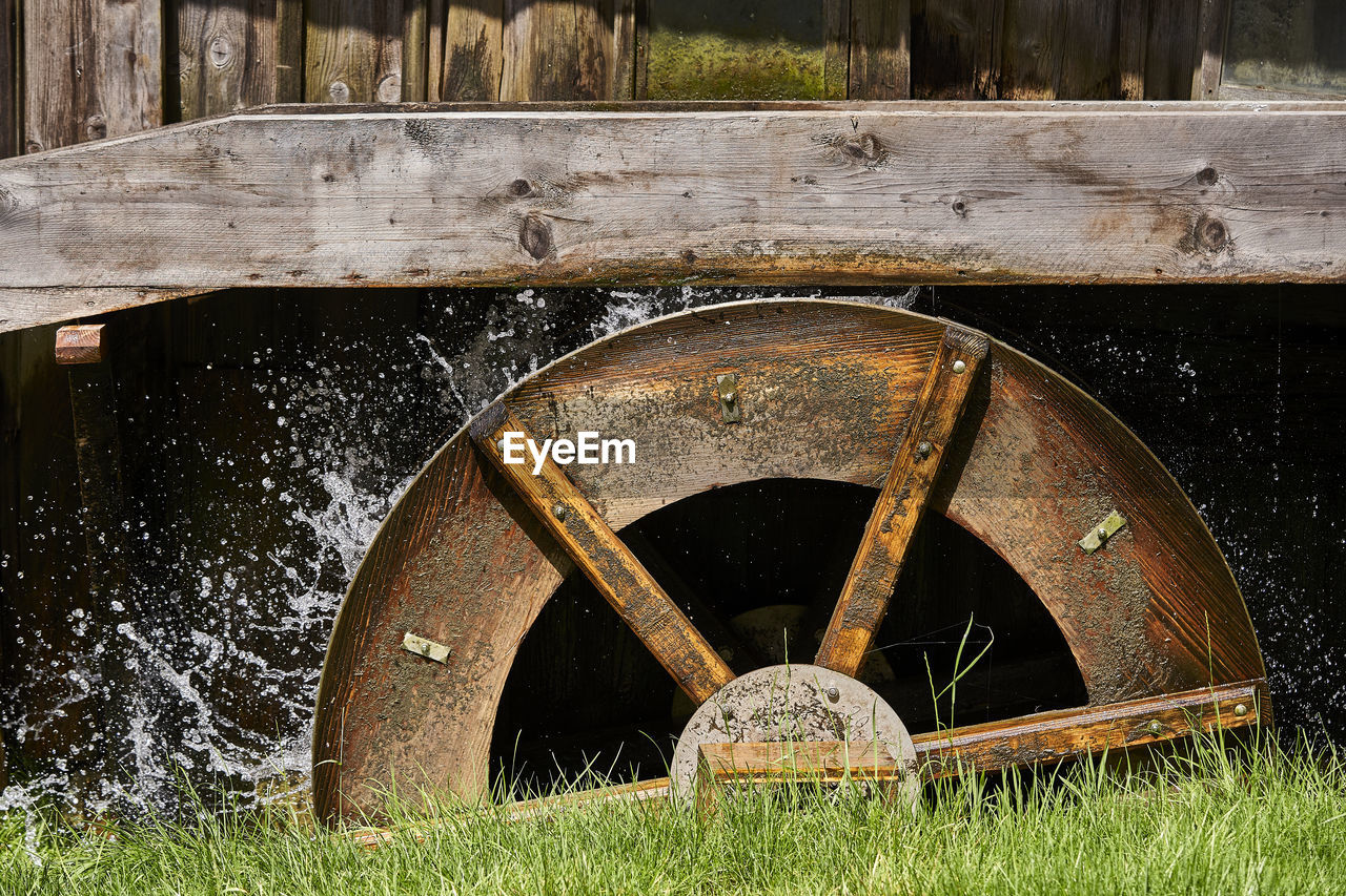 OLD RUSTY WHEEL ON FIELD BY WATER