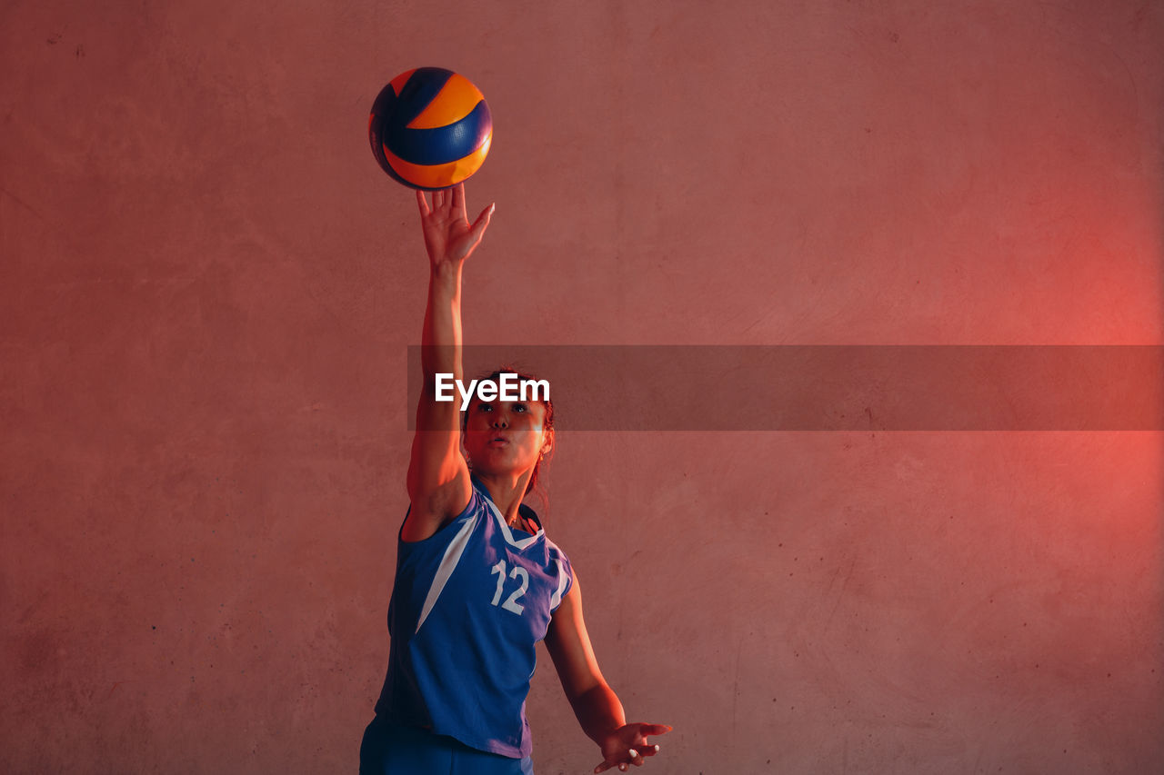 Woman playing volleyball against wall