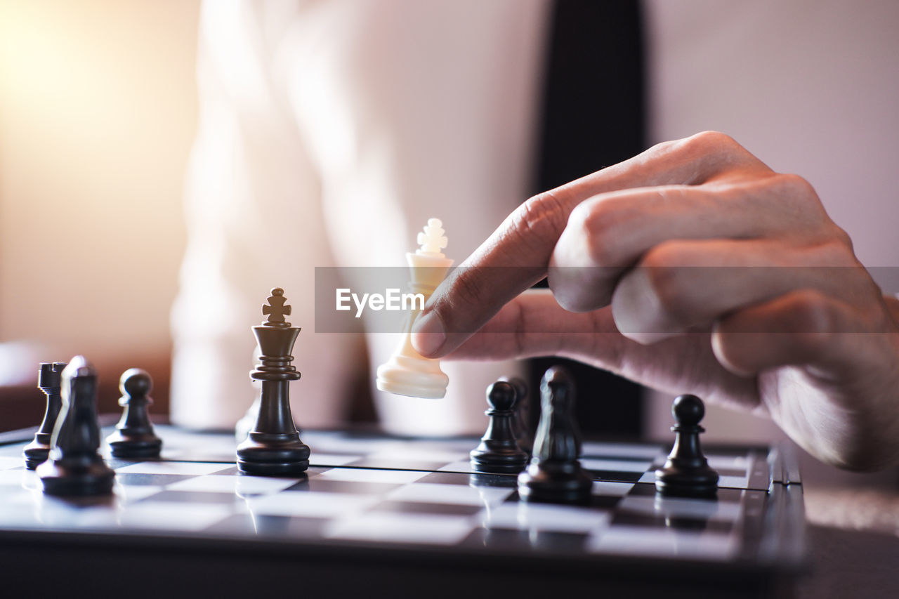 Midsection of businessman playing chess in office