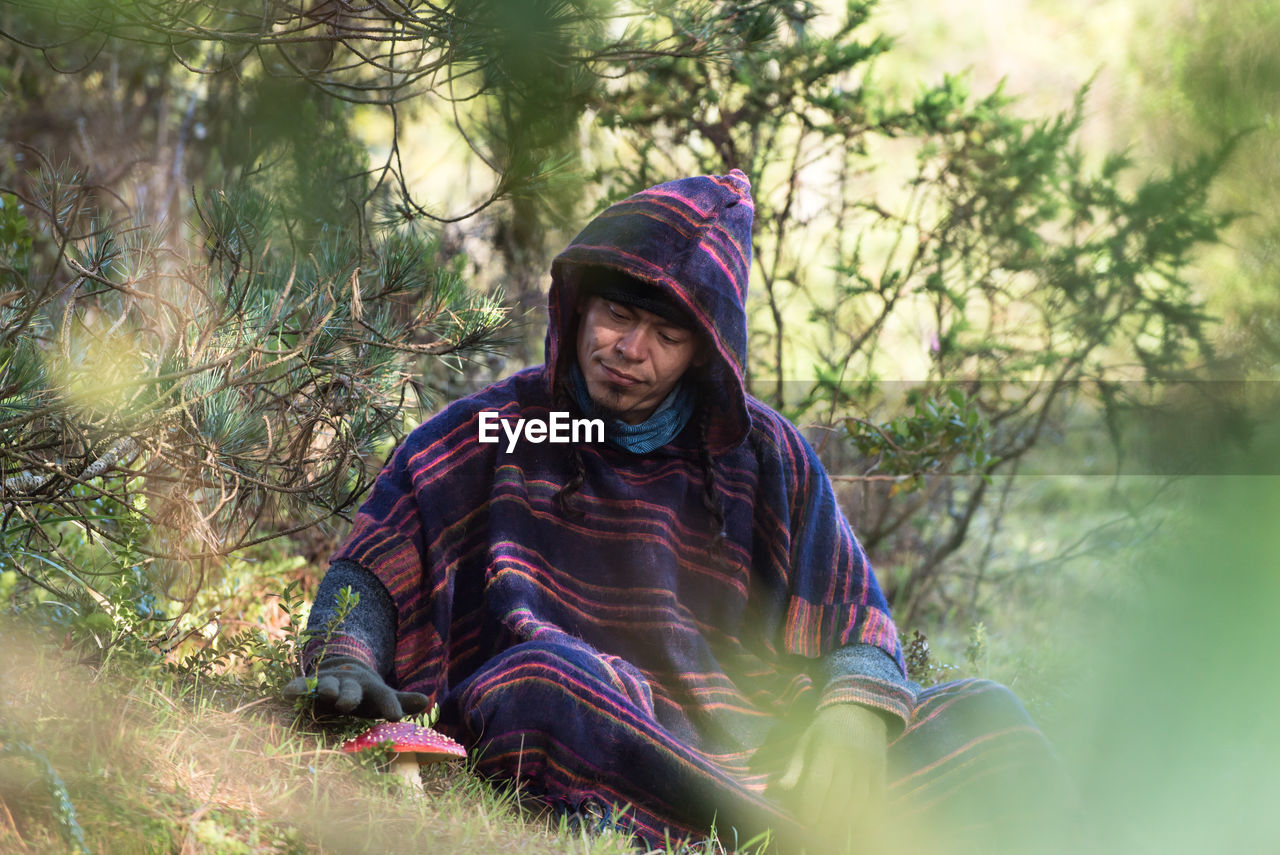 Colombian native american man in traditional clothing sitting in forest