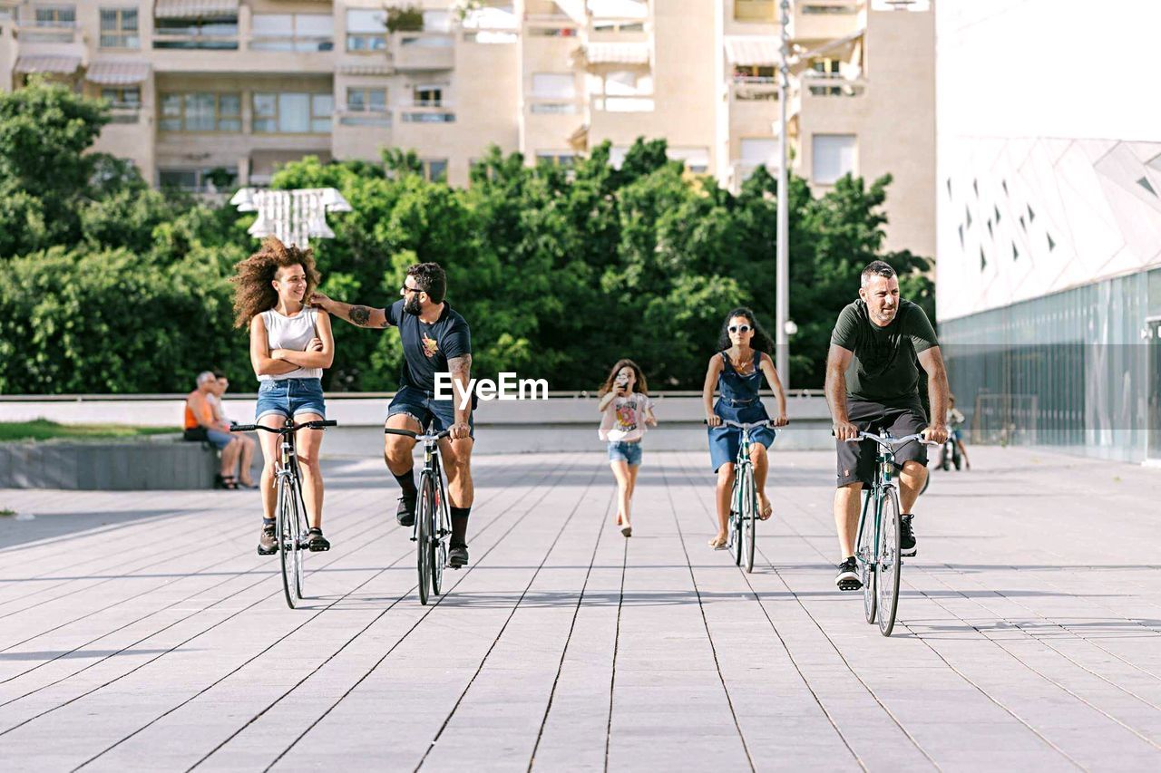 PEOPLE RIDING BICYCLE ON CITY STREET IN TOWN