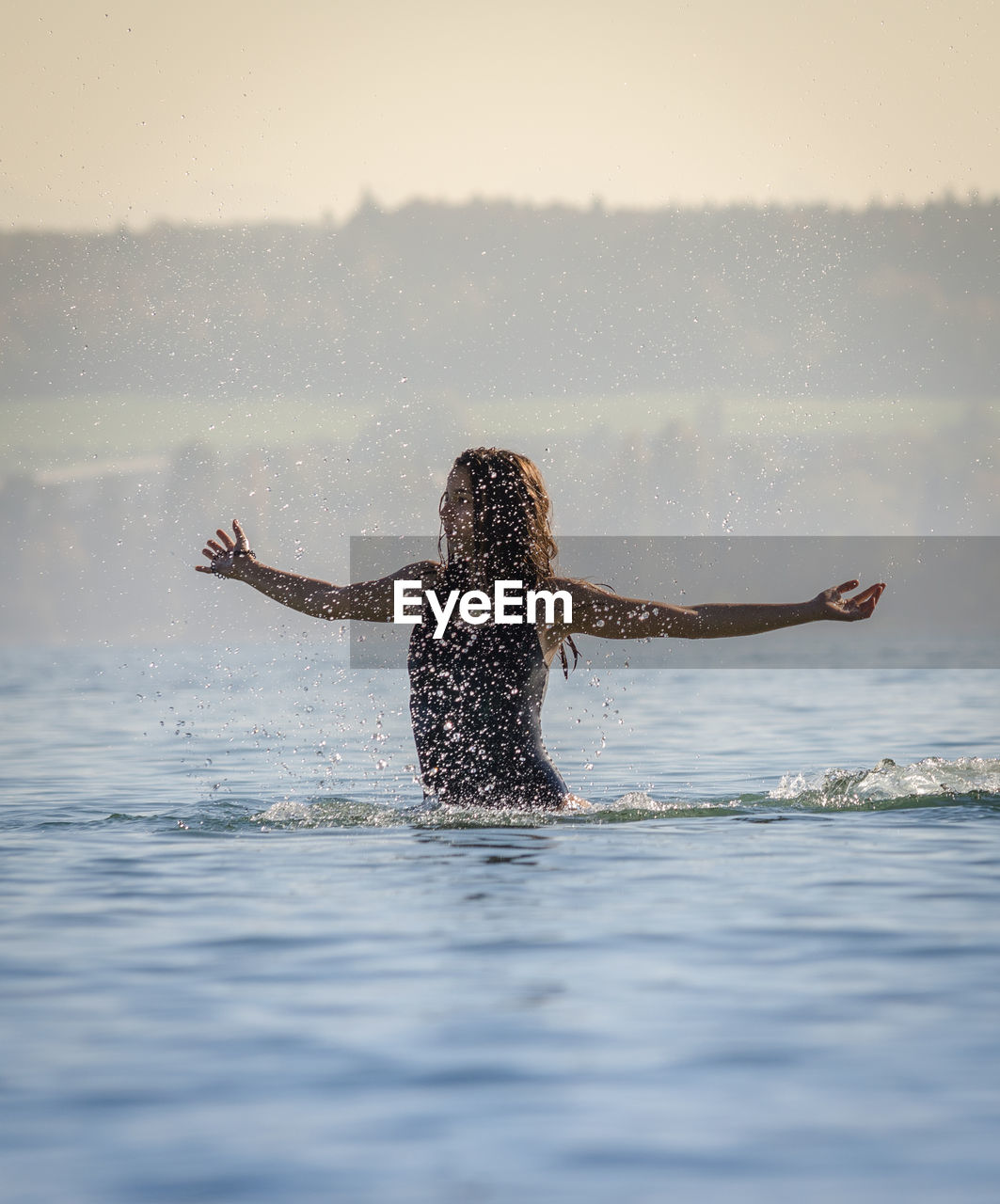 Woman splashing water in lake against sky