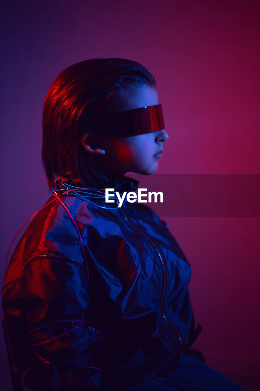 Portrait cyberpunk boy child in vr glasses in blue and red tones. game, virtual reality