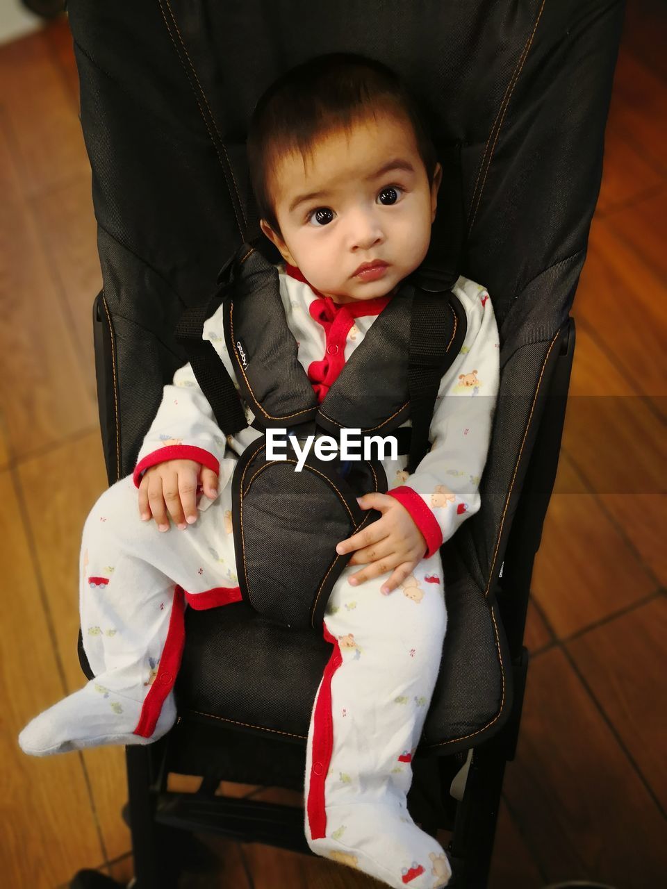 Portrait of cute baby boy sitting in stroller at home