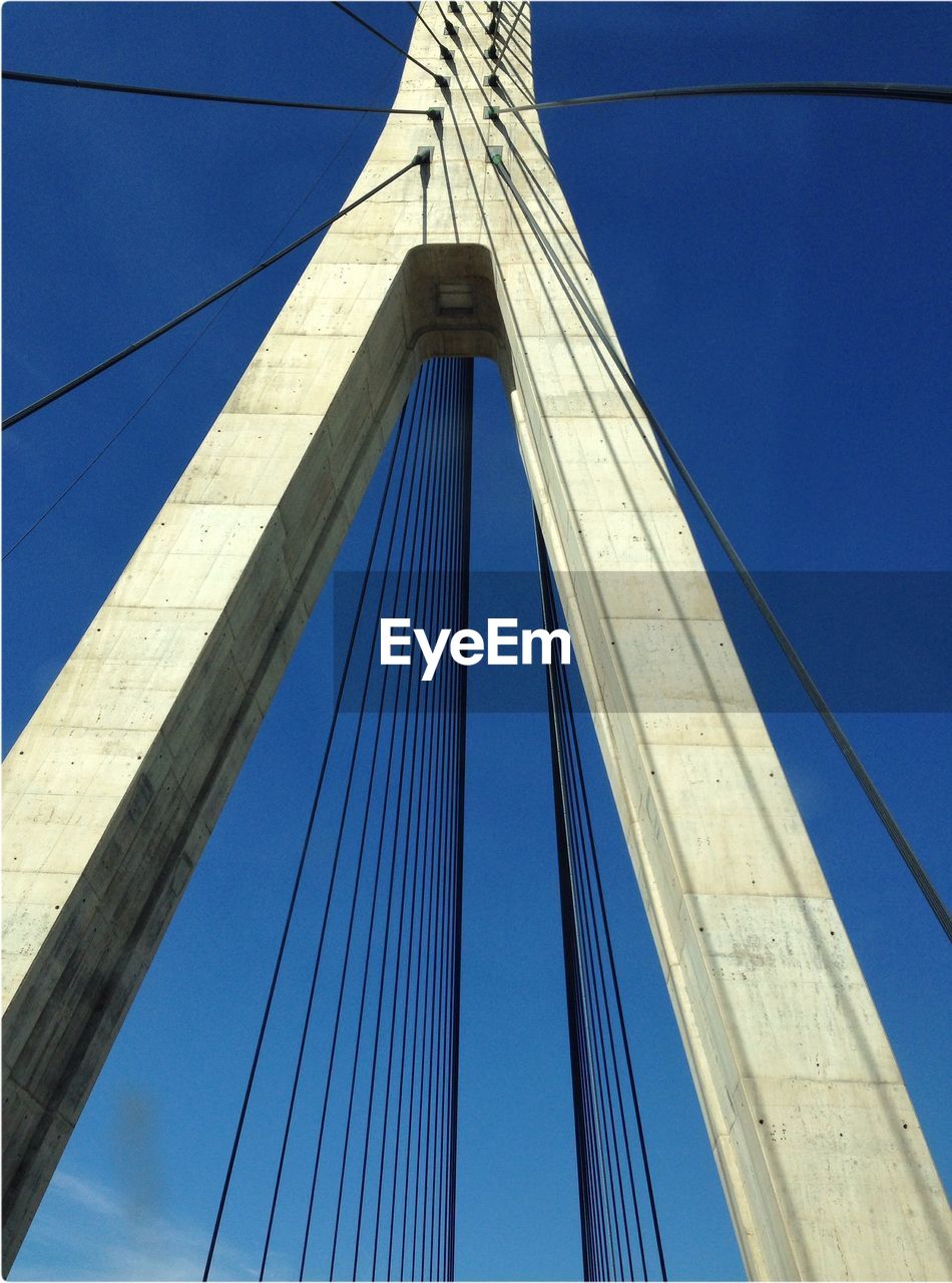 Low angle view of suspension bridge,. blue sky, white structure.