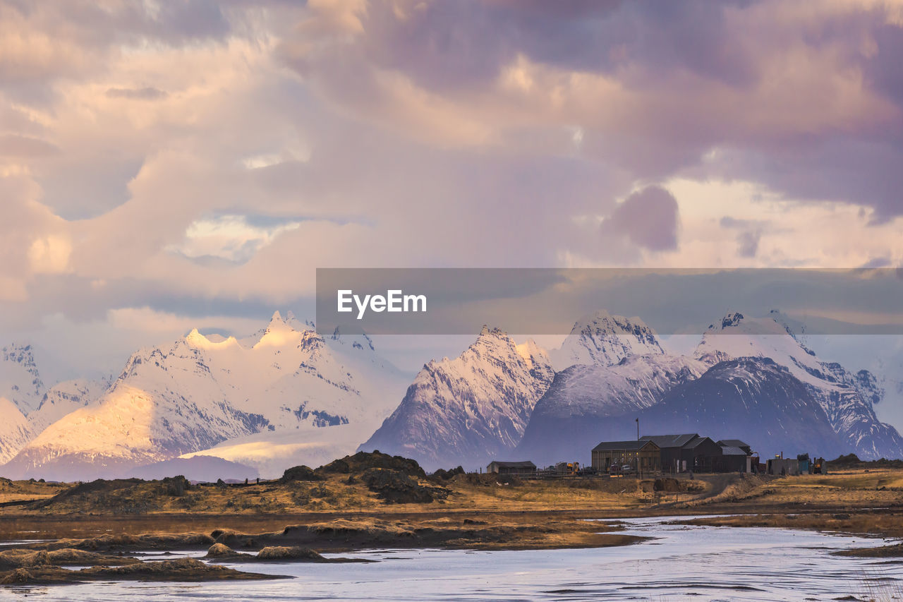 Scenic view of rocky mountains with snow in winter near stockness beach under cloudy sky in iceland