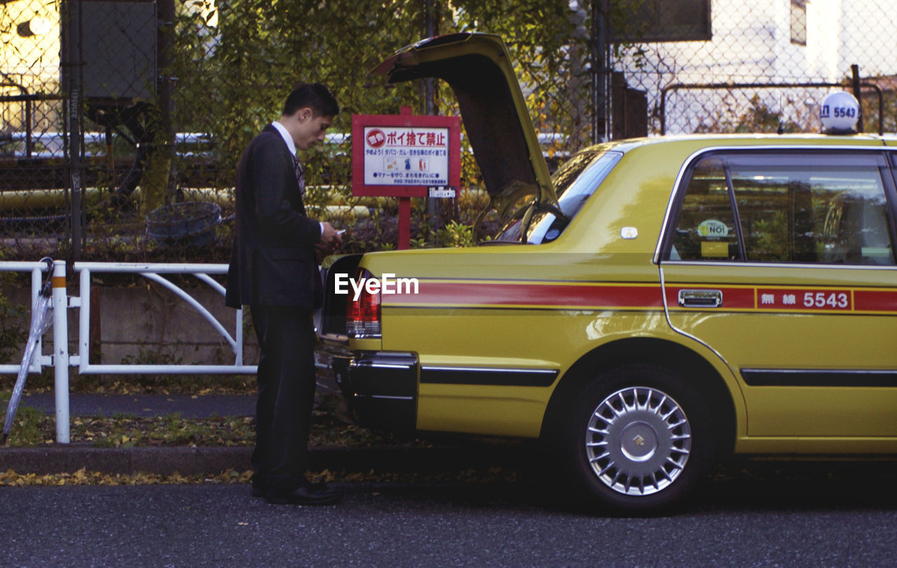 SIDE VIEW OF MAN STANDING IN CAR