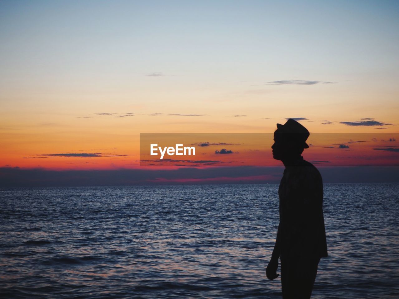 Silhouette man standing at beach during sunset