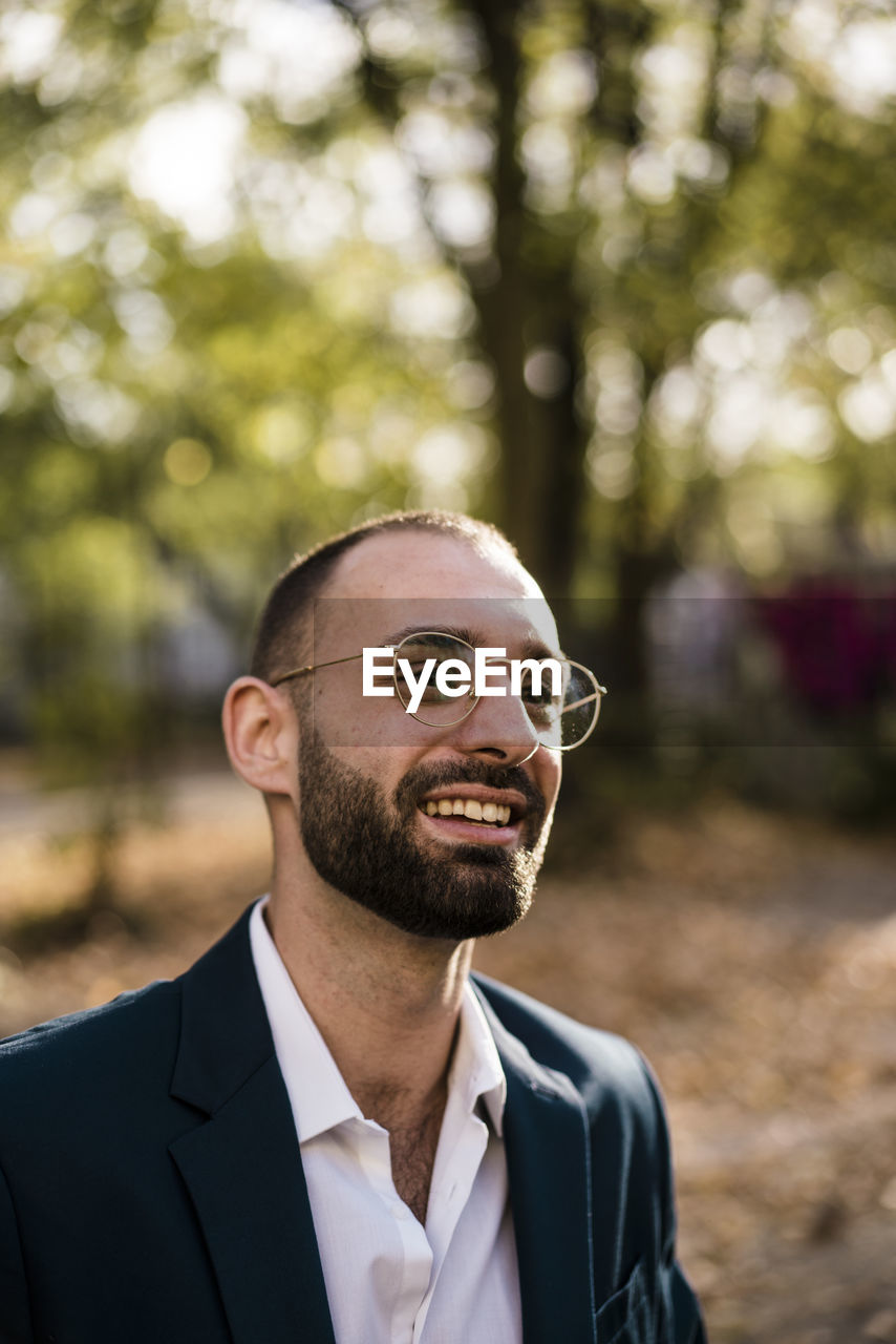 Happy businessman wearing eyeglasses in park