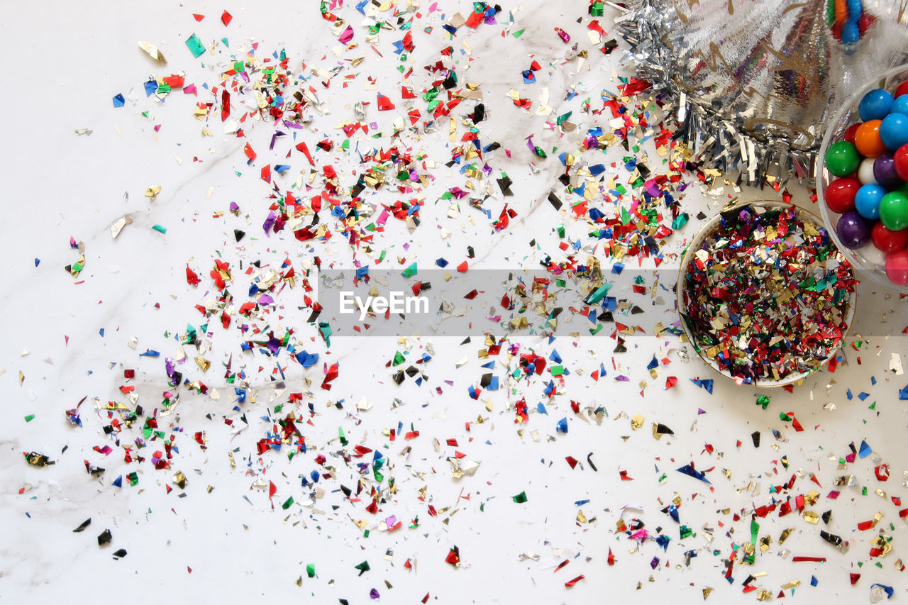 High angle view of colorful confetti with gumballs on marble