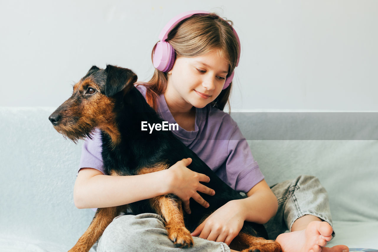 Young woman with dog sitting on sofa at home