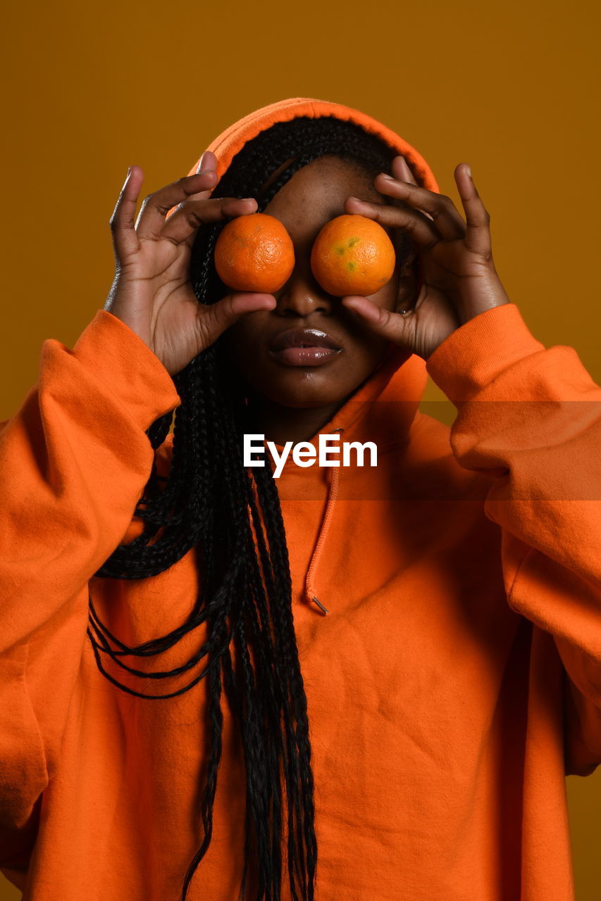 PORTRAIT OF SMILING WOMAN HOLDING ORANGE FRUIT