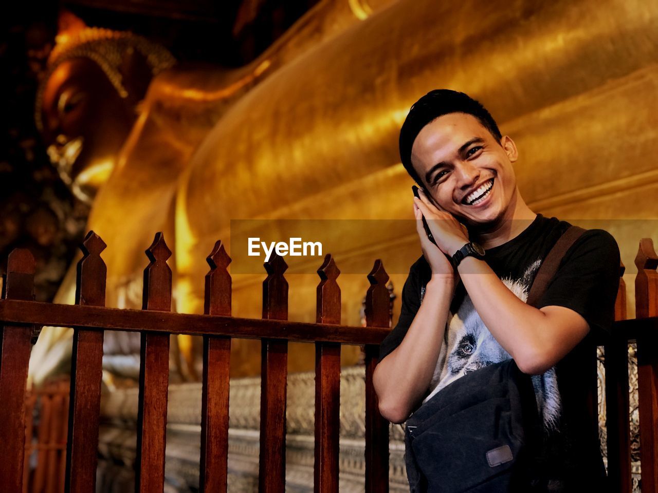 Portrait of smiling young man against buddha temple